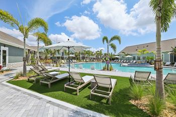 A poolside area with lounge chairs and palm trees. at The Junction at Rockledge Apartments, Rockledge, FL